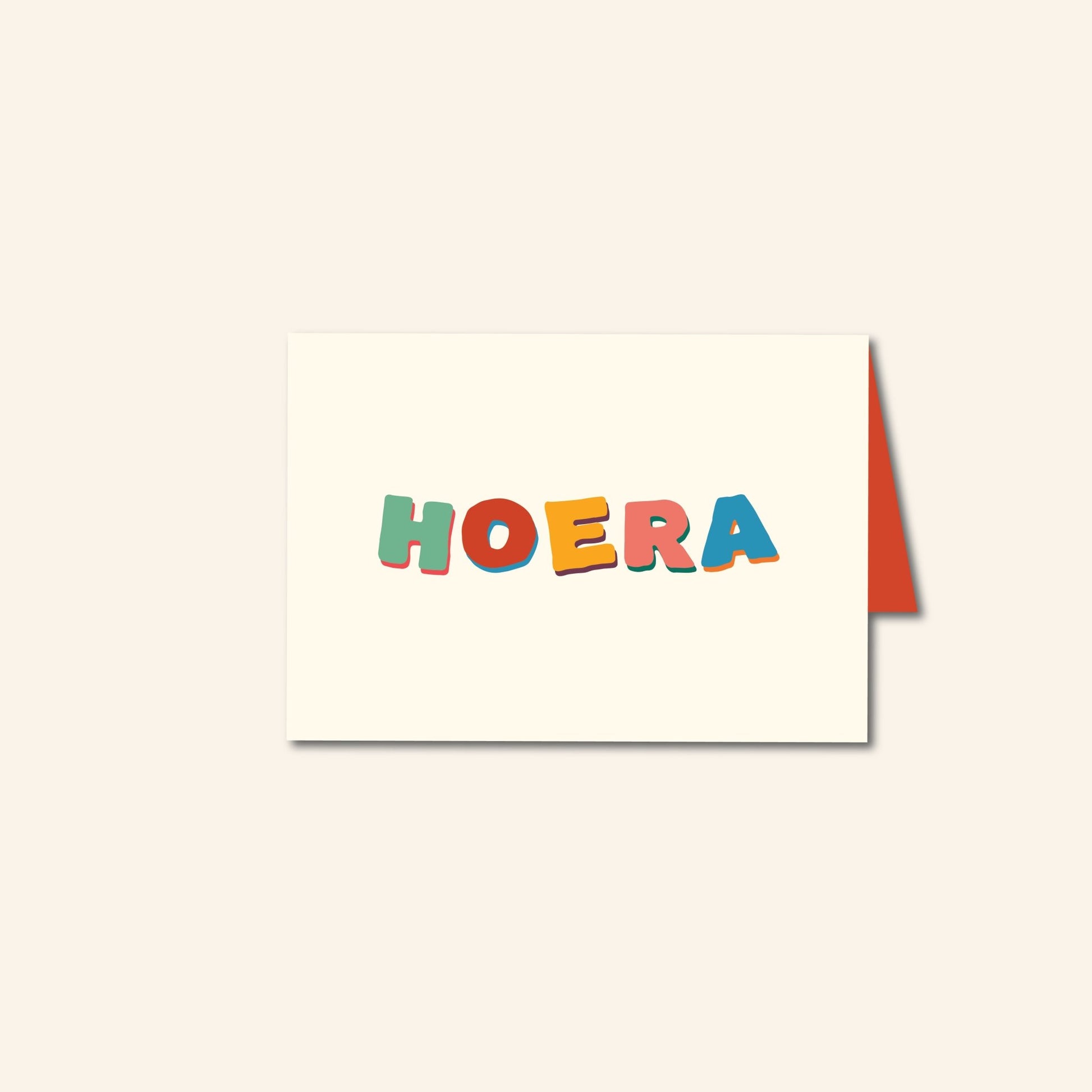 Wenskaart met kleurrijke handgetekende letters “Hoera” op een crèmekleurige achtergrond – feestelijk ontwerp van Studio Bloos.