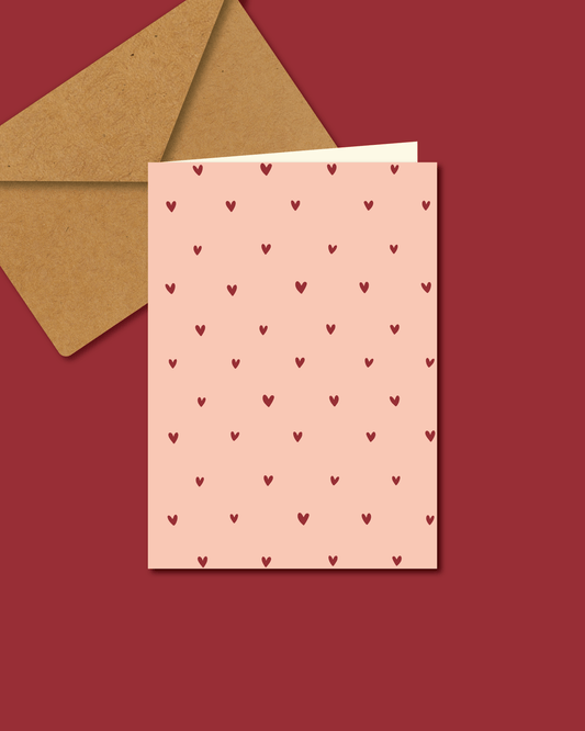 "Roze A6-wenskaart met hartjesmotief, blanco binnenkant" "Liefdevolle roze wenskaart met hartjes, geschikt voor elke gelegenheid" "Romantische A6-kaart in het roze met hartjesdesign" "Roze kaart met hartjes voor Valentijn, verjaardag of zomaar" "Wenskaart A6, roze met hartjes, op rood oppervlak" 