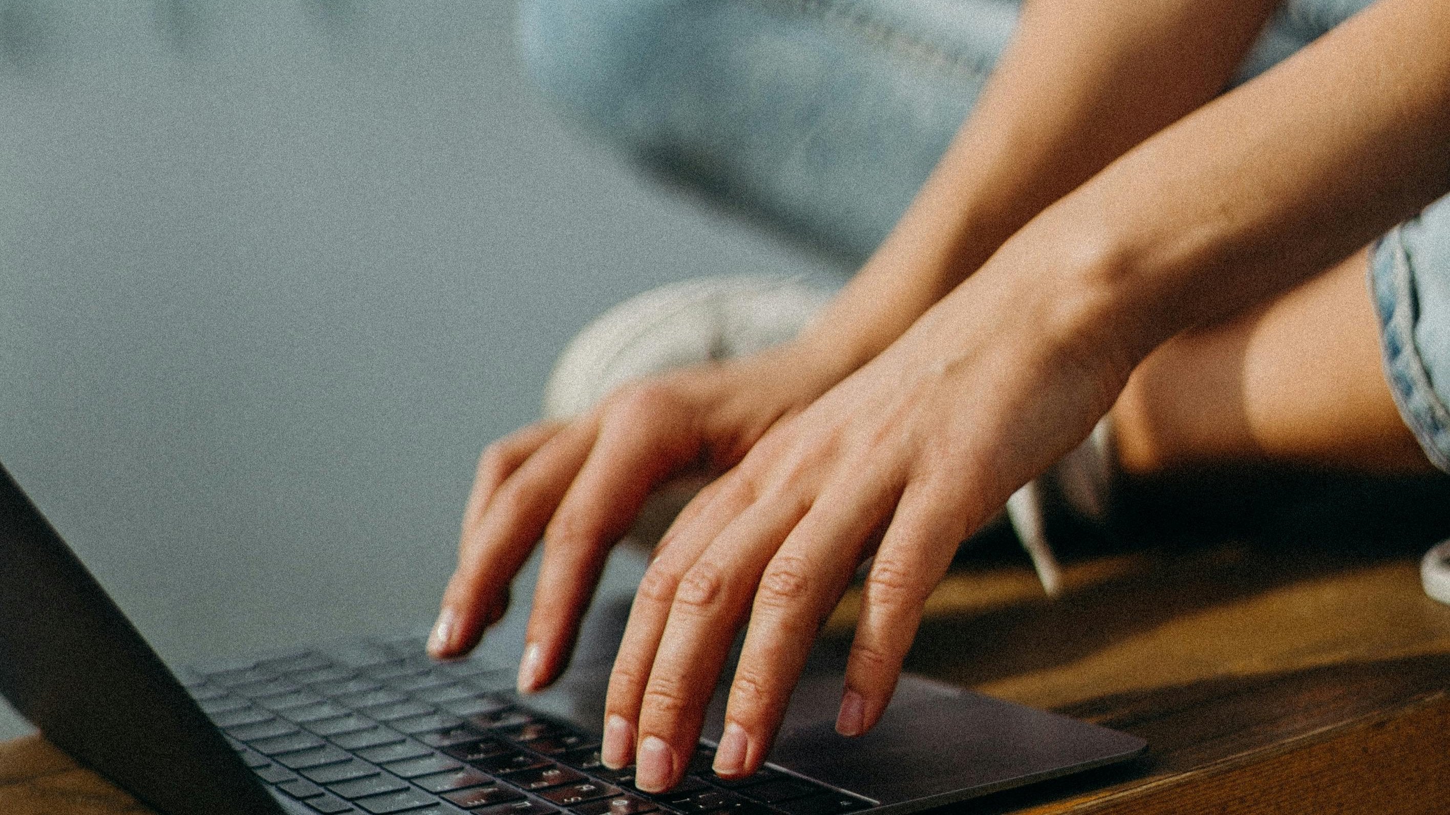"Typende handen aan laptop als symbool voor creatief proces en maatwerk grafisch design – professioneel ontwerp op aanvraag"