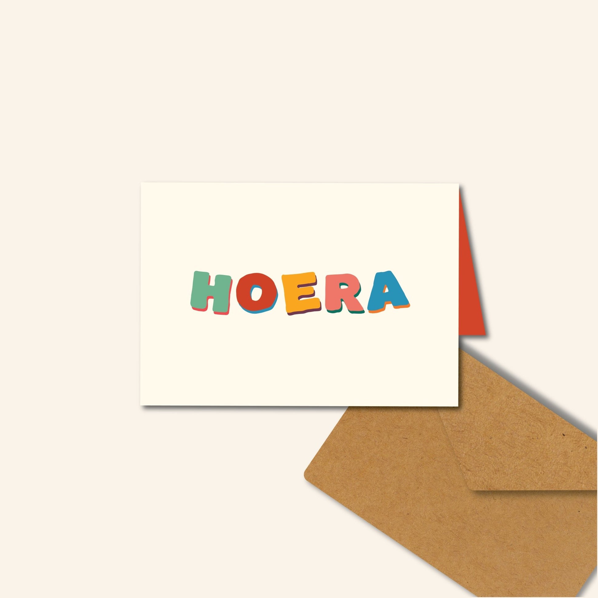 Wenskaart met kleurrijke handgetekende letters “Hoera” op een crèmekleurige achtergrond – feestelijk ontwerp van Studio Bloos.